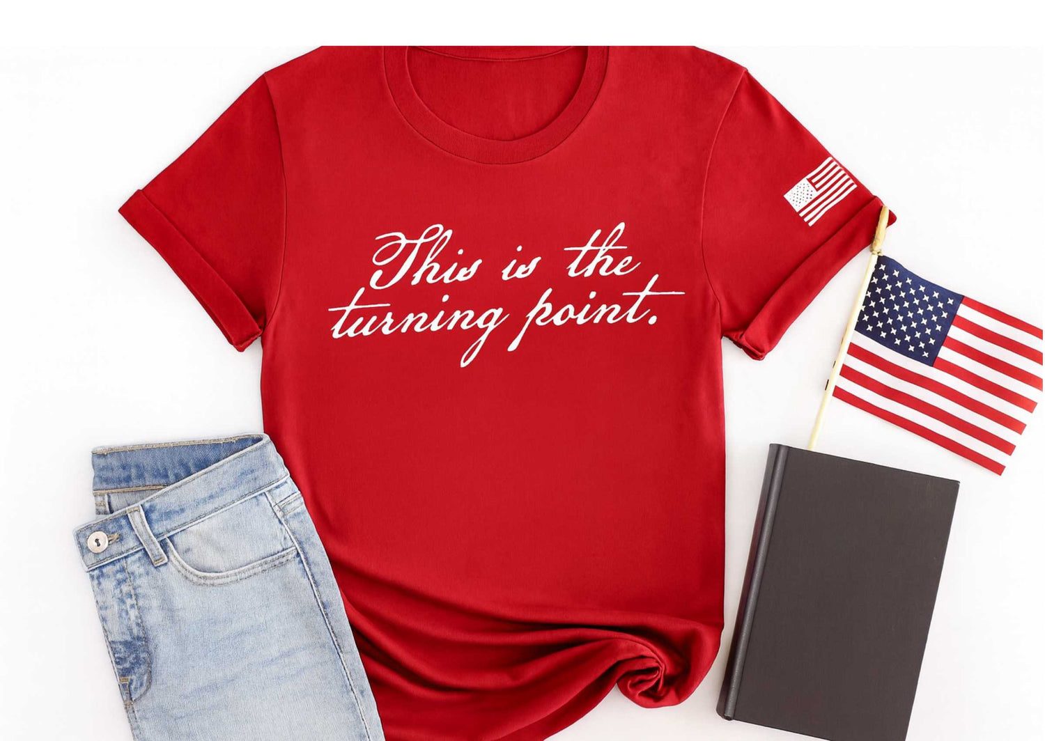 This is the turning point printed in white in a handwritten script font on a red t shirt.  A distressed american flag in white is printed on the sleeve.