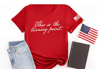 This is the turning point printed in white in a handwritten script font on a red t shirt.  A distressed american flag in white is printed on the sleeve.
