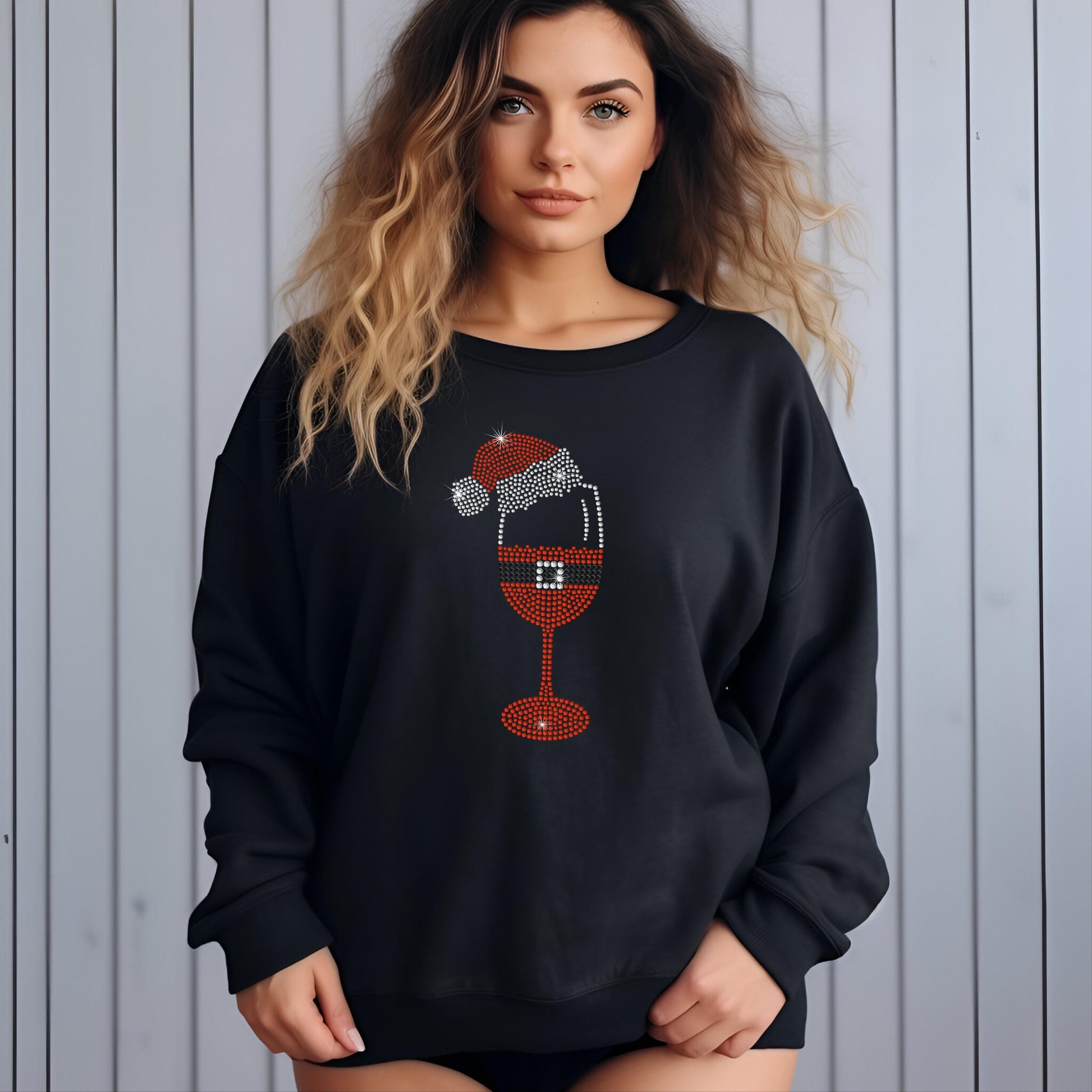 Blonde woman wearing a black sweatshirt with a sparkly rhinestone Santa wine glass design, posing in front of a light background.