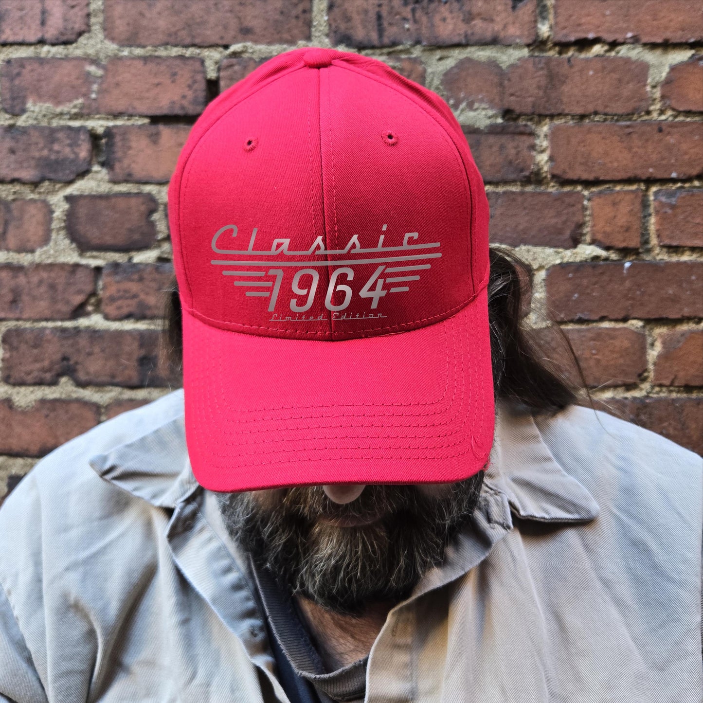 Red Classic 1964 Limited Edition baseball cap displayed on bearded man against a brick wall.