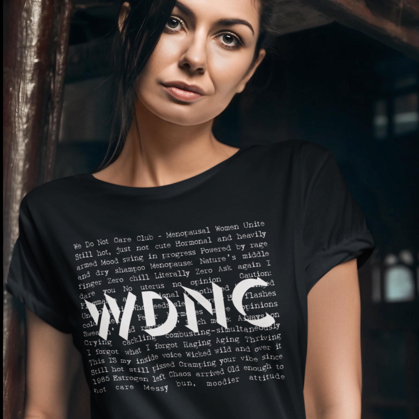 Black t-shirt with funny menopause text design and bold WDNC (We Don Not Care Club) lettering, worn by women with confidence and attitude.
