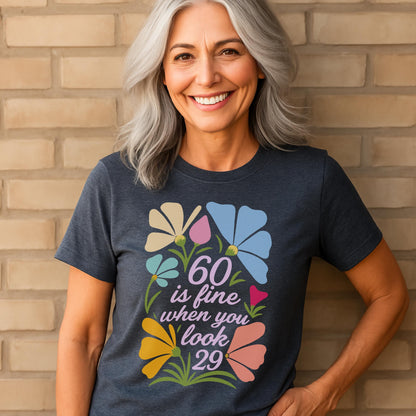Smiling woman in navy shirt with floral “60 is fine when you look 29” birthday design.