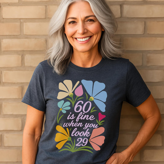 Smiling woman in navy shirt with floral “60 is fine when you look 29” birthday design.