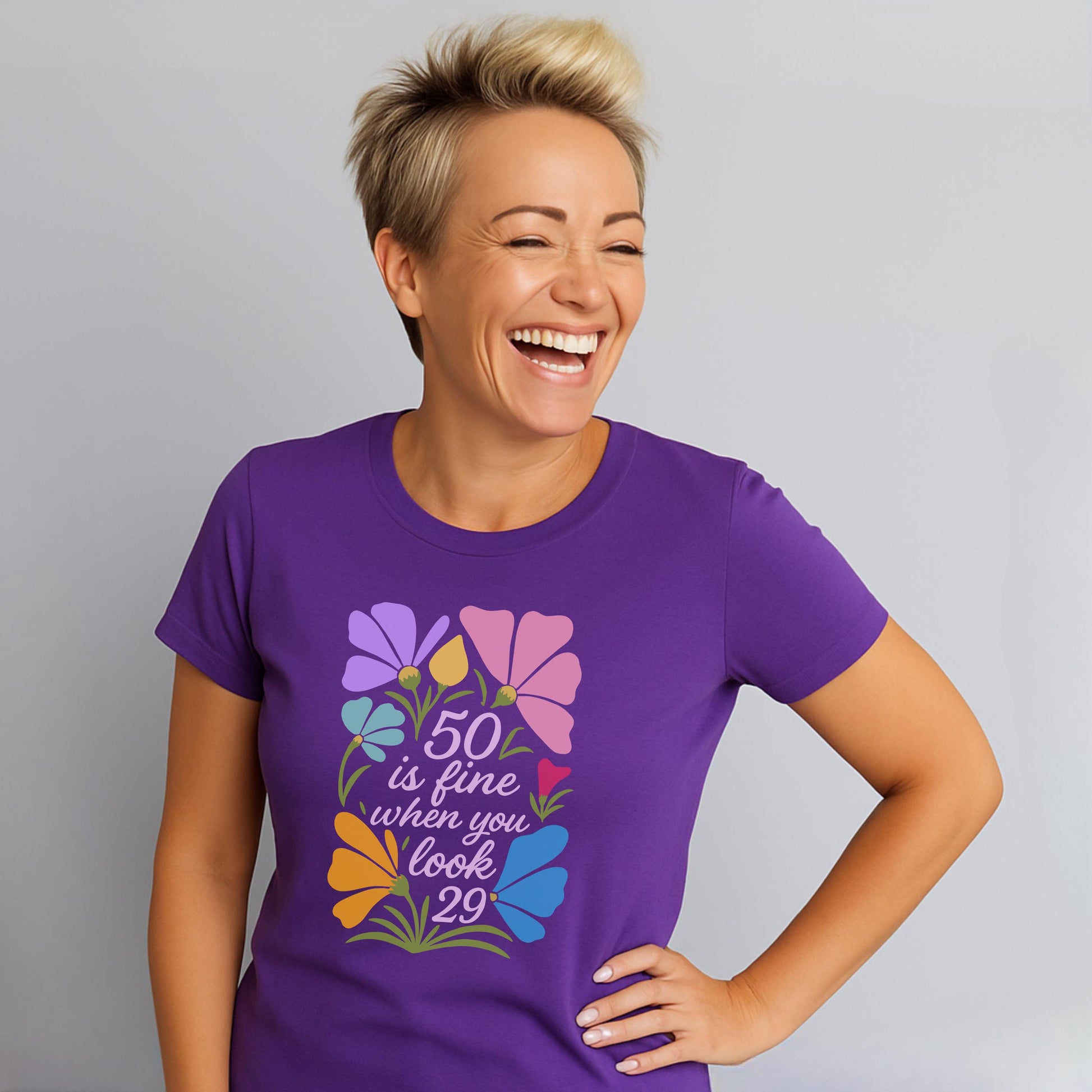 Woman in purple shirt with “50 is fine when you look 29” text and pastel flowers.
