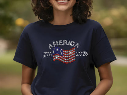 Smiling woman wearing navy t-shirt with rhinestone USA flag and America 250th anniversary design outdoors.