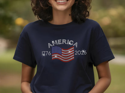 Smiling woman wearing navy t-shirt with rhinestone USA flag and America 250th anniversary design outdoors.