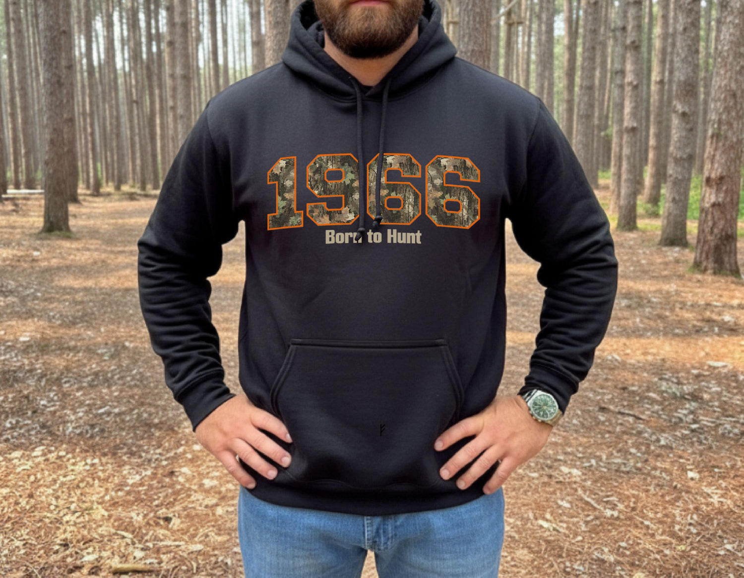 Man wearing black hunting hoodie with camouflage 1966 graphic and “Born to Hunt” text, outdoor forest setting, rugged hunting apparel.  Great gift for a hunter celebrating his/her's 60th birthday