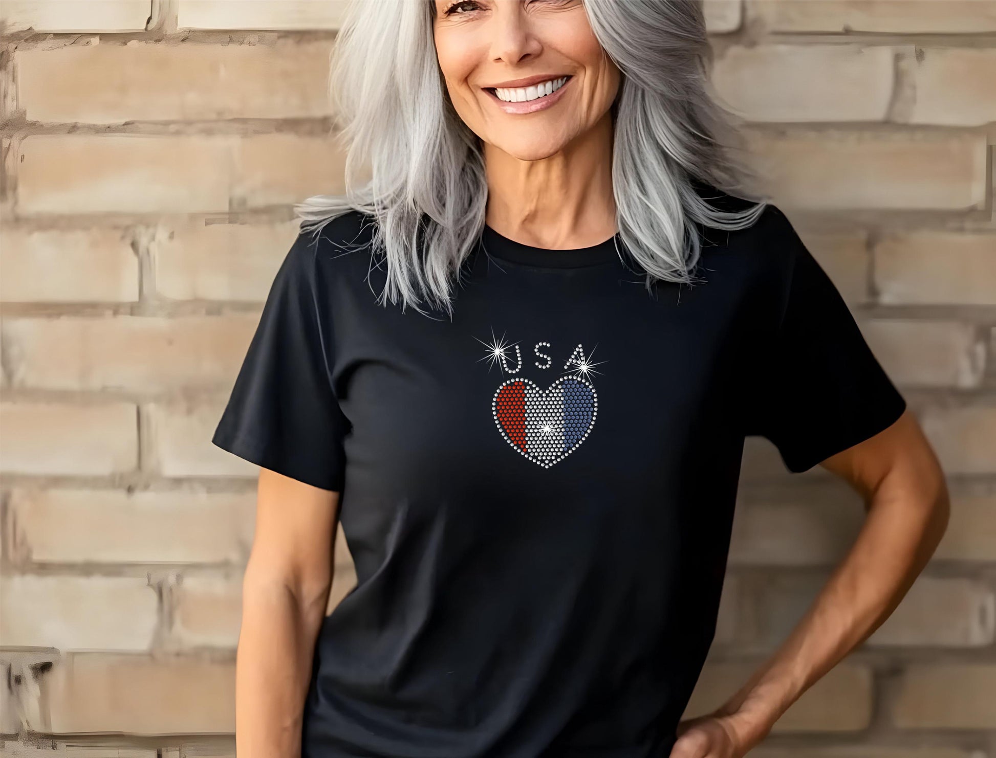 Black Ladies T Shirt with the word "USA" in clear rhinestones, a heart in red white and blue rhinestone is under the word.  Just in time for USA's 250th Anniversary.