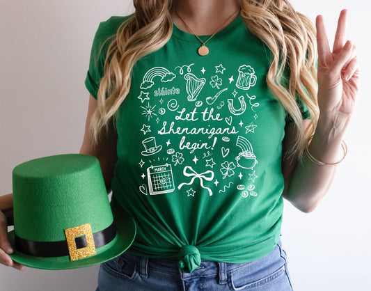 Green St Patrick’s Day t shirt with let the shenanigans begin doodle shamrock design