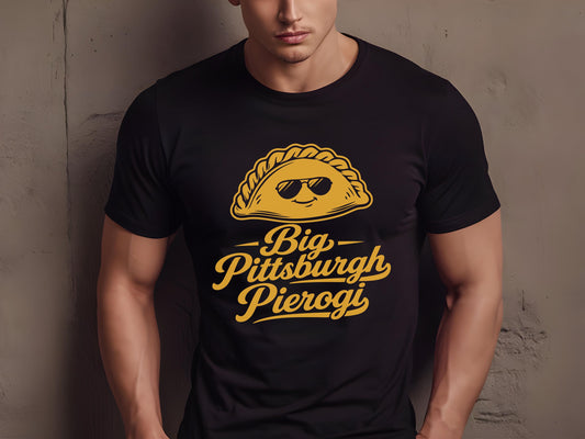 Man wearing a black comfortable t-shirt featuring a cute cartoon pierogi with sunglasses and text reading Big Pittsburgh Pierogi.